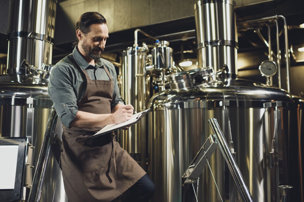 Brewer taking notes on his beer in a brewery.